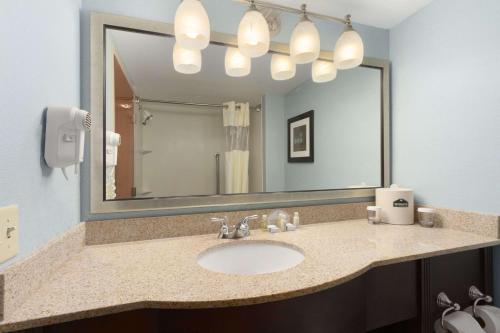 a bathroom with a sink and a large mirror at Wingate by Wyndham, Fayetteville NC in Fayetteville