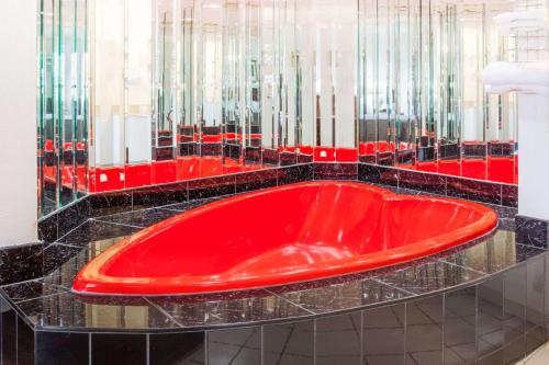 a red bath tub in a black tile bathroom at Howard Johnson by Wyndham Niagara Falls in Niagara Falls