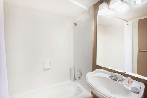 Baño blanco con lavabo y espejo en Howard Johnson by Wyndham Yuma en Yuma
