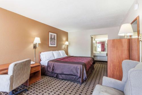 a hotel room with a bed and a desk and chairs at Knights Inn Murfreesboro in Murfreesboro