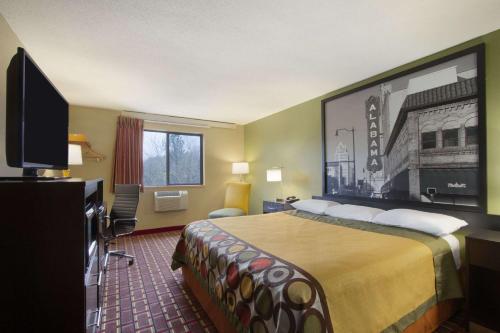 a hotel room with a bed and a flat screen tv at Super 8 by Wyndham Homewood Birmingham Area in Birmingham