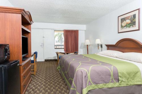 a hotel room with a bed and a flat screen tv at Super 8 by Wyndham Riviera Beach West Palm Beach in Riviera Beach