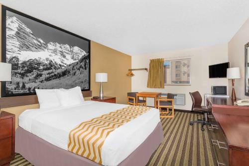 ラブランドにあるTravelodge by Wyndham Loveland/Fort Collins Areaのベッドとデスクが備わるホテルルームです。