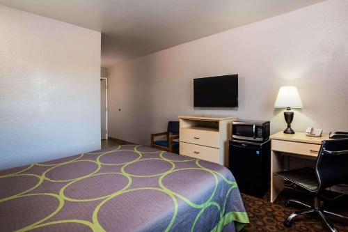 a hotel room with a bed and a desk with a computer at Super 8 by Wyndham Vacaville in Vacaville