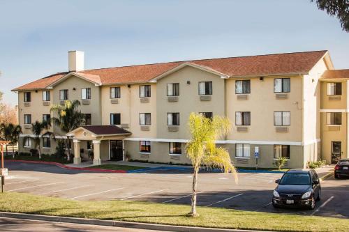 a building with a car parked in a parking lot at Super 8 by Wyndham Vacaville in Vacaville