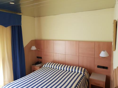 Hostal Milenium في Els Monjos: غرفة نوم بسرير بخطوط زرقاء وبيضاء