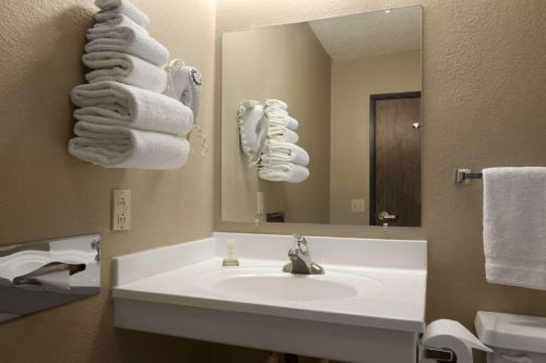 ein Badezimmer mit einem Waschbecken, einem Spiegel und Handtüchern in der Unterkunft Super 8 by Wyndham Blackwell in Blackwell
