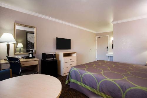 a hotel room with a bed and a desk and a television at Super 8 by Wyndham Vacaville in Vacaville