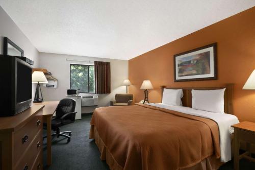 a hotel room with two beds and a television at Travelodge by Wyndham Muskegon in Muskegon