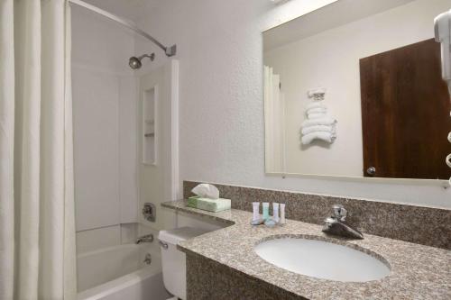 La salle de bains est pourvue d'un lavabo, de toilettes et d'un miroir. dans l'établissement Travelodge by Wyndham Muskegon, à Muskegon