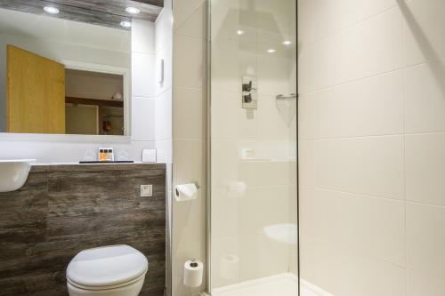 uma casa de banho com um WC e uma cabina de duche em vidro. em The Woodlands Event Centre em Wyboston