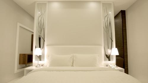a bedroom with a large white bed with two lamps at Broad Almkan Apart Hotel in Taif