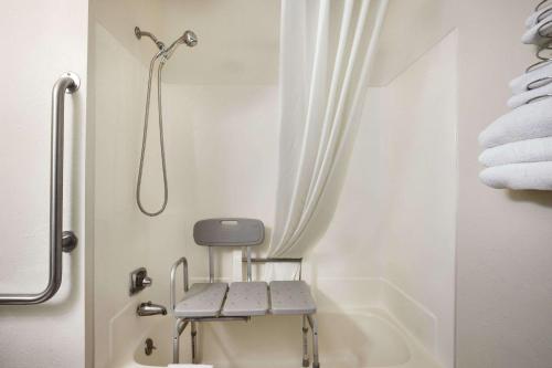 a bathroom with a shower and a tub with towels at Travelodge by Wyndham La Porte/Michigan City Area in LaPorte