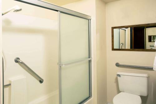 a bathroom with a toilet and a glass shower door at Travelodge by Wyndham Ocean Front in Sunset Beach