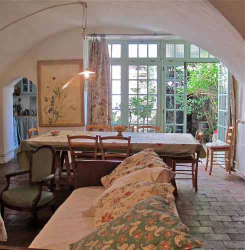 une salle à manger avec une table, des chaises et des fenêtres dans l'établissement Les Asphodèles Amélie, à Saint-Hippolyte-du-Fort