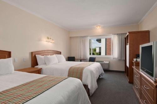 Cette chambre comprend 2 lits et une télévision à écran plat. dans l'établissement Travelodge by Wyndham Kamloops, à Kamloops