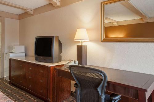 a room with a desk with a television and a chair at Knights Inn Greensburg in Greensburg