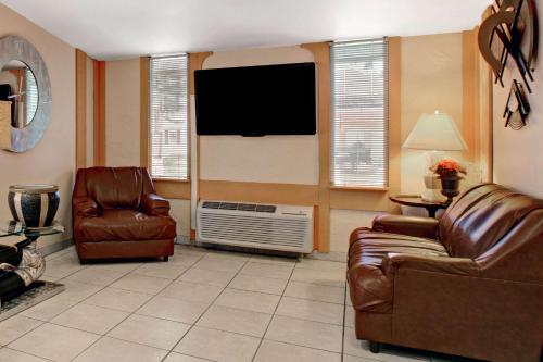 a living room with two leather chairs and a flat screen tv at Knights Inn Greensburg in Greensburg