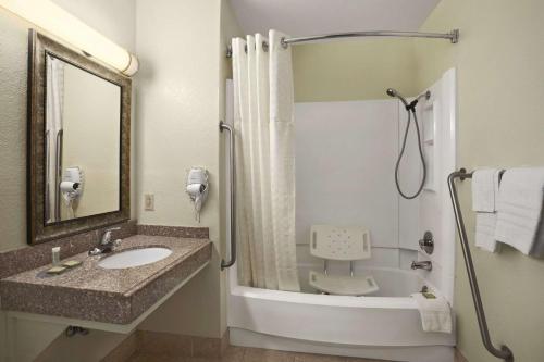 y baño con lavabo, ducha y bañera. en Super 8 by Wyndham Carlsbad en Carlsbad