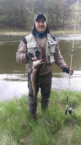 a man holding a fish in his hand next to a river at Toftemo Turiststasjon in Dovre