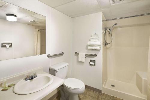 Super 8 by Wyndham Redfield في Redfield: حمام أبيض مع حوض ومرحاض