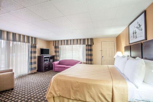 a hotel room with a bed and a pink chair at Travelodge by Wyndham South Burlington in Burlington