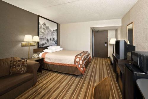 a hotel room with a bed and a flat screen tv at Super 8 by Wyndham Redfield in Redfield