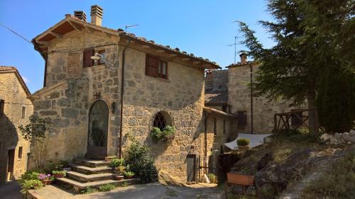 una vieja casa de piedra con escaleras que conducen a ella en Il Borgo Del Lupo, en Sarteano