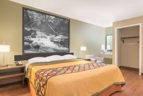 a hotel room with a bed with a large picture on the wall at Super 8 by Wyndham Bryant Little Rock Area in Bryant