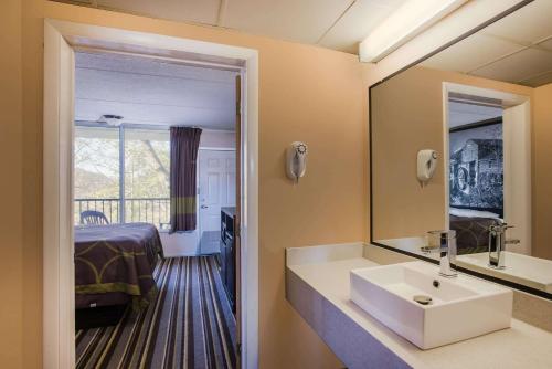 a bathroom with a sink and a mirror and a bed at Super 8 by Wyndham Sevierville Riverside in Sevierville