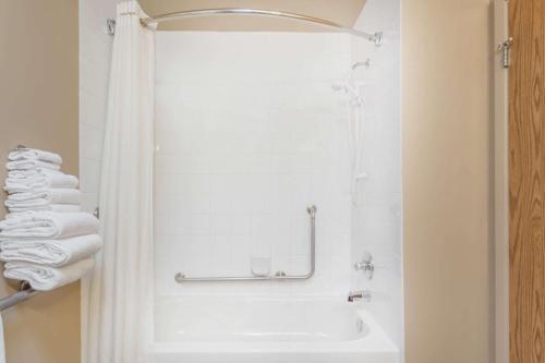 a bathroom with a shower and a sink and towels at Super 8 by Wyndham Pincher Creek AB in Pincher Creek