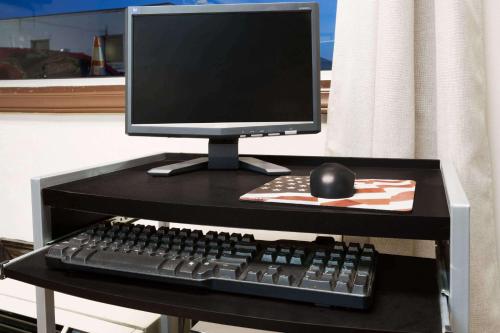 a computer monitor and a keyboard and mouse on a desk at Super 8 by Wyndham Greensboro in Greensboro