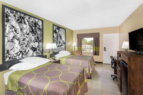 a hotel room with two beds and a flat screen tv at Super 8 by Wyndham Sarasota Near Siesta Key in Sarasota