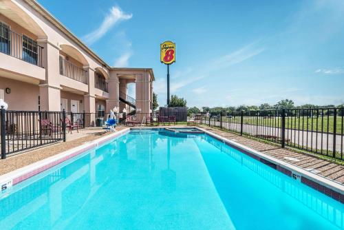 a swimming pool in front of a building at Super 8 by Wyndham Greenville in Greenville