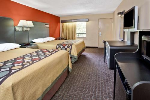 a hotel room with two beds and a flat screen tv at Super 8 by Wyndham Kissimmee/Maingate/Orlando Area in Orlando