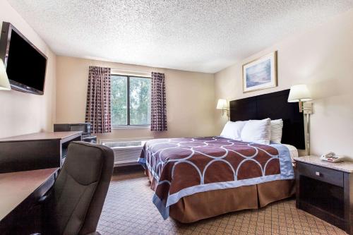 a hotel room with a bed and a desk at Super 8 by Wyndham Cleveland TX in Cleveland