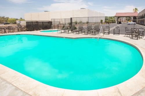 a large blue swimming pool with chairs and tables at Travelodge by Wyndham Indio in Indio