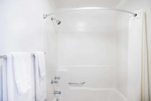 a white bathroom with a shower with white towels at Travelodge by Wyndham Lake George NY in Lake George