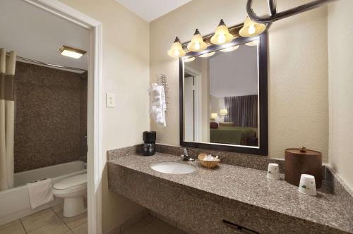 a bathroom with a sink and a toilet and a mirror at Travelodge by Wyndham New Orleans Harvey Hotel in Harvey