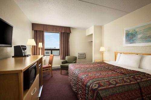 ein Hotelzimmer mit einem Bett und einem TV in der Unterkunft Travelodge by Wyndham Edmonton West in Edmonton