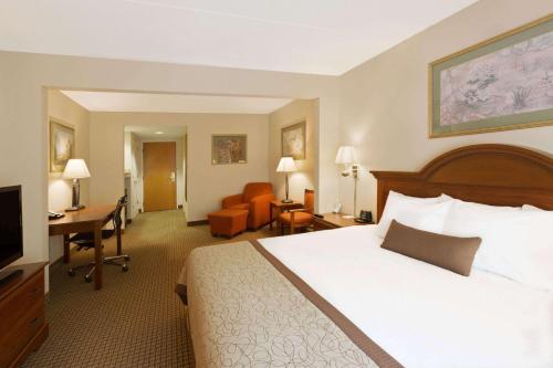 Wingate by Wyndham Charlotte Airport في تشارلوت: غرفة الفندق بسرير كبير ومكتب