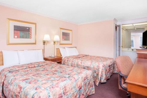 Una habitación de hotel con dos camas y un escritorio. en Knights Inn - Augusta, en Augusta
