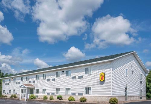a large white building with a red sign on it at Super 8 by Wyndham Phillips in Phillips
