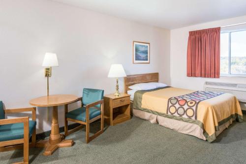a hotel room with a bed and a desk and a table at Super 8 by Wyndham West Middlesex/Sharon Area in West Middlesex
