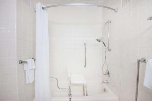 a white bathroom with a shower and a white chair at Super 8 by Wyndham Erie/I 90 in Erie