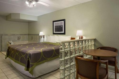 1 dormitorio con 1 cama, mesa y sillas en Super 8 by Wyndham South Padre Island, en South Padre Island
