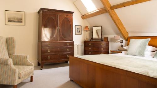 a bedroom with a large bed and a chair at Priory Wareham in Wareham