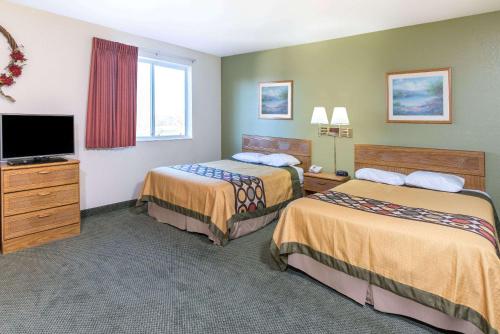 a hotel room with two beds and a flat screen tv at Super 8 by Wyndham West Middlesex/Sharon Area in West Middlesex