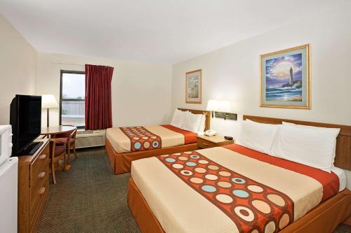 a hotel room with two beds and a flat screen tv at Super 8 by Wyndham Hampshire IL in Hampshire