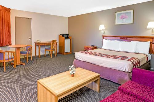 une chambre d'hôtel avec un lit et une table dans l'établissement Super 8 by Wyndham Upland Ontario CA, à Upland